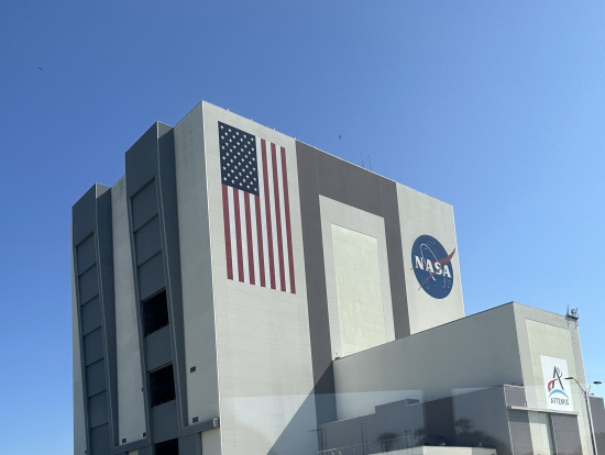 バス車中から見えるスペースシャトル組立棟(一続きの建物として世界最大体積)